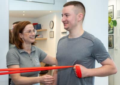 Fizjoterapeuta we Wrocławiu nadzorujący ćwiczenia rehabilitacyjne z taśmą.